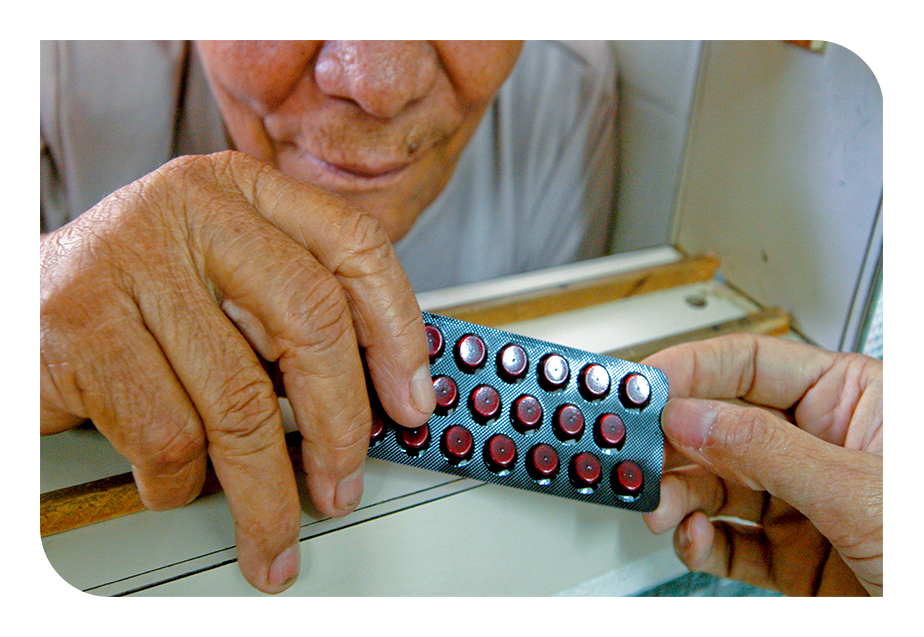 Pessoa idosa recebendo uma cartela de medicamento. 