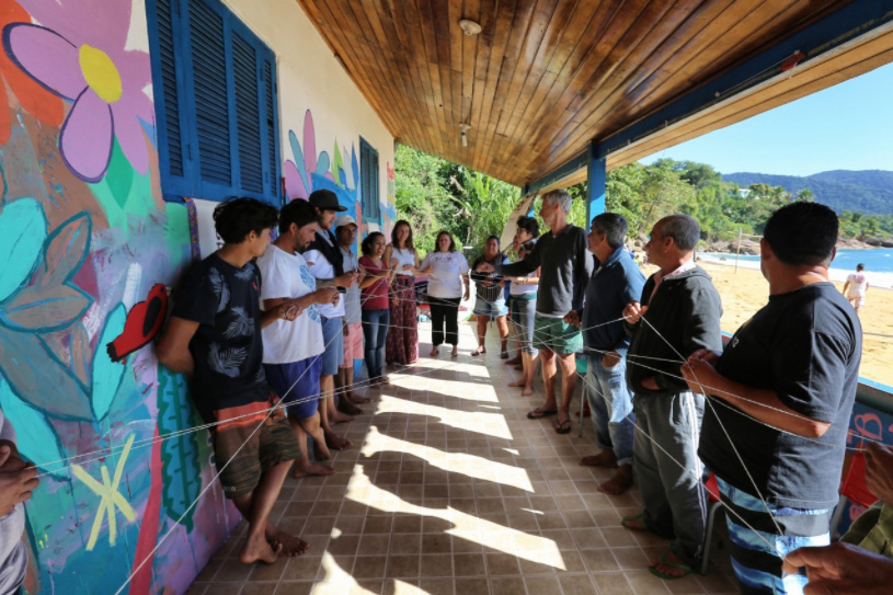 Mulher empurrando uma jangada na beira de um rio. 