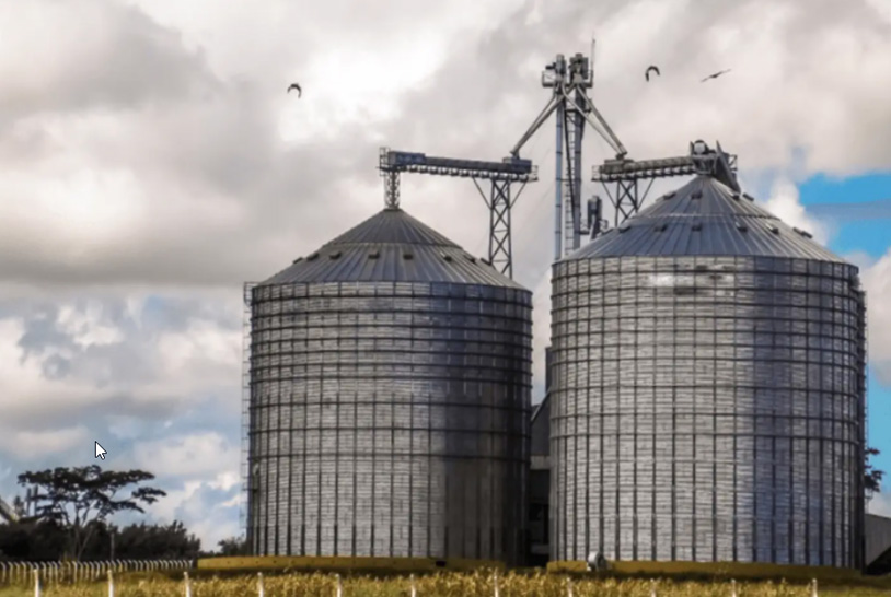 Foto de um campo com dois grandes silos de metal.